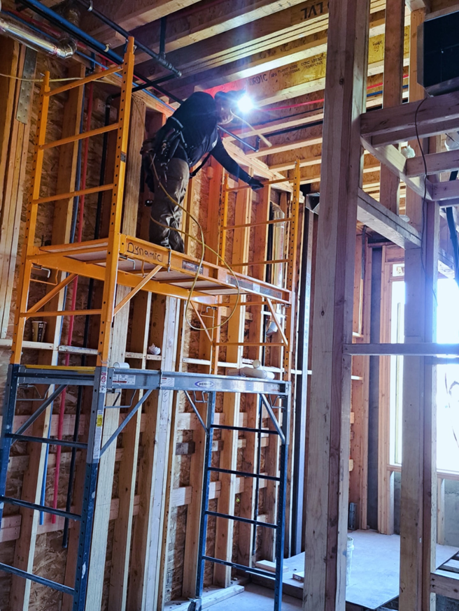 An electrician on scaffolding installing new wiring in a framed building for Haddad Electric LLC in Jersey City, NJ.