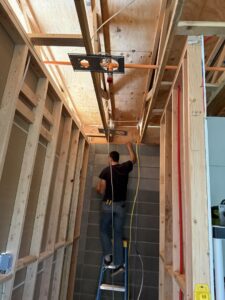 An electrician installing new wiring in a framed wall and ceiling for Sparks By Rabbit LLC in Scottsdale, AZ.