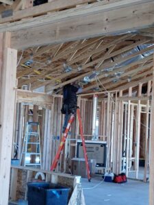 An electrician installing electrical wiring in the ceiling of a new construction project for The Specialist Electrical Contractor in Albuquerque, NM.