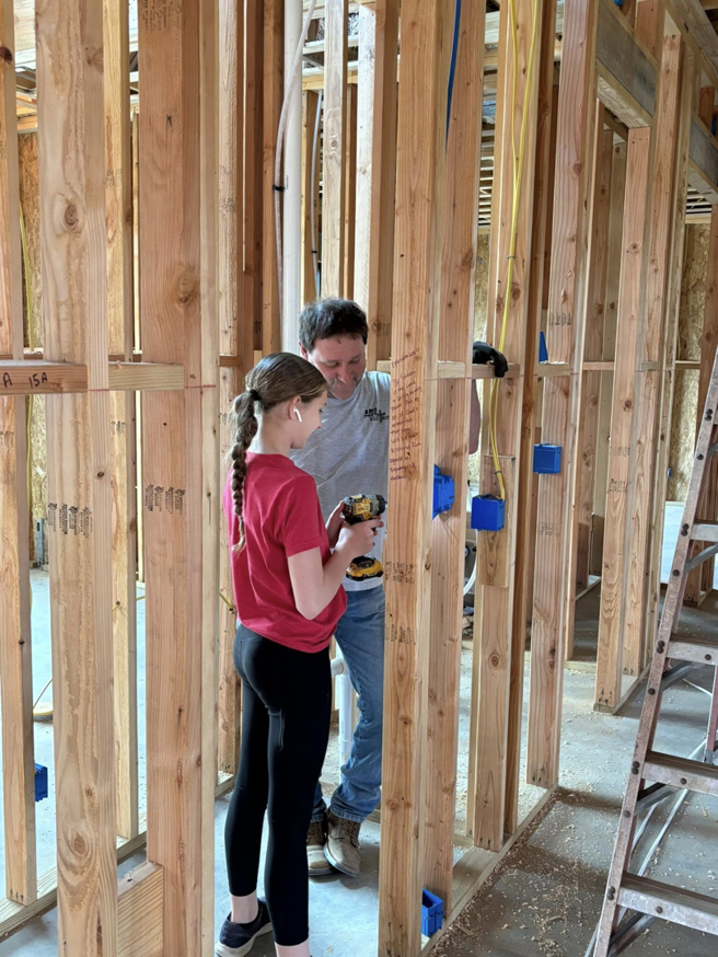 An electrician installing new electrical wiring and blue junction boxes in a home under construction by ASTS Electric in West Monroe, LA.