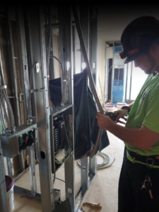 An electrician installing electrical wiring and a panel in a new construction project for Personal Electric LLC in Baltimore, MD.