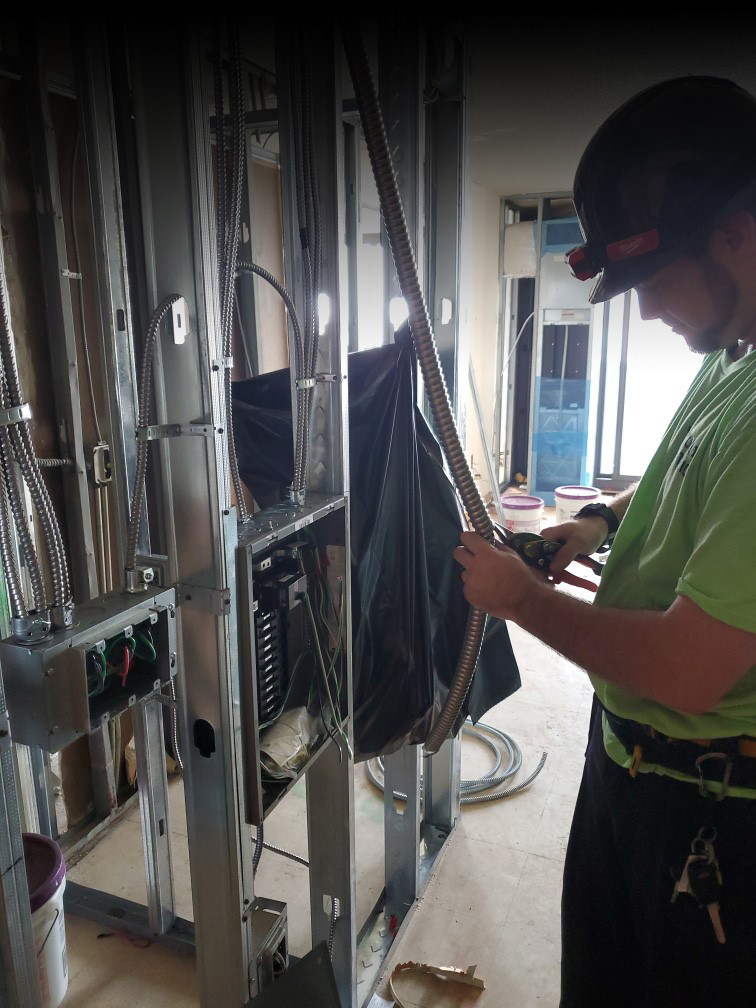 An electrician installing electrical wiring and a panel in a new construction project for Personal Electric LLC in Baltimore, MD.