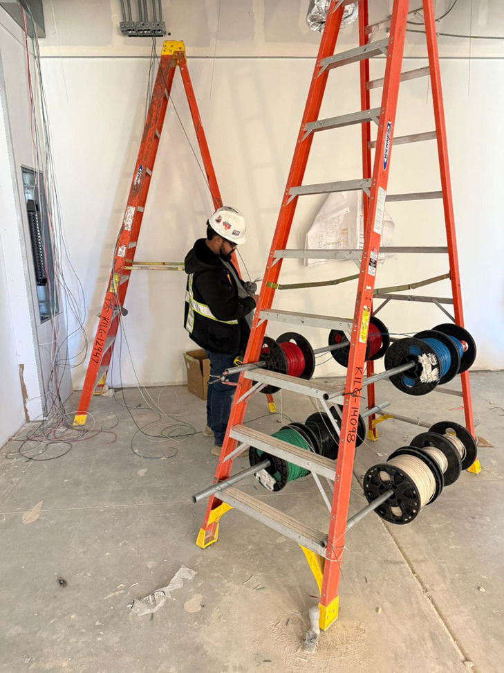 An electrician from Reyes Electric Company installing new wiring on a construction site in Dallas, TX.
