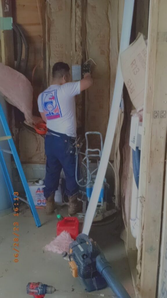 An electrician installing new wiring and electrical boxes in a wall during a construction project by Delta Electric in Germantown, MD.