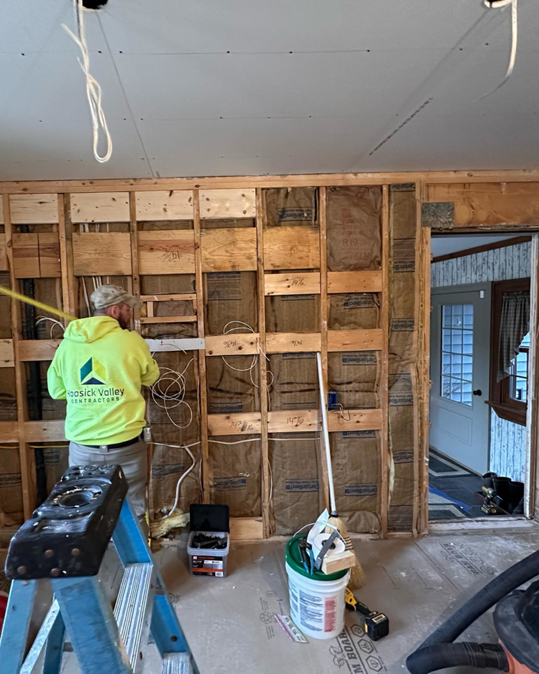 An electrician installing new wiring in an open wall during a renovation project by Elite Electric in Valley Falls, NY