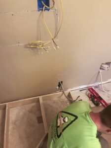 An electrician from Steadfast Electric, LLC installing new wiring in a wall during a renovation project in Baton Rouge, LA.