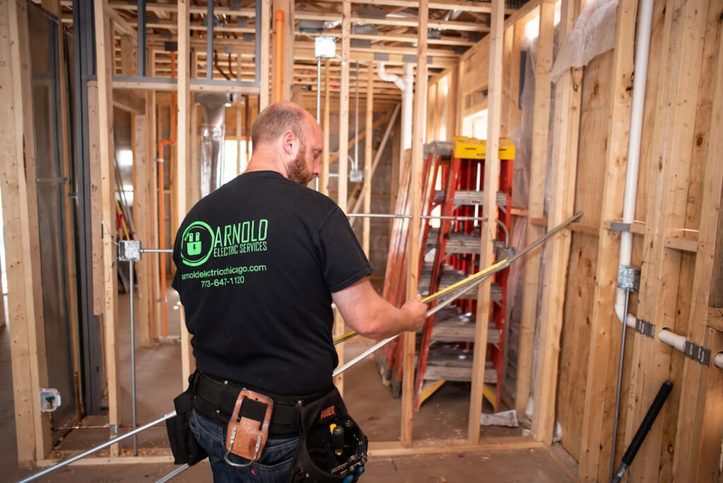 An electrician from Arnold Electrical Repair & Installation measuring conduit for new wiring in a residential construction project in Chicago, IL.
