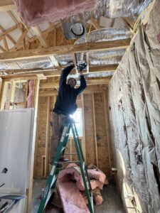 An electrician on a ladder installing electrical components in a new construction project by Ace Electrical Services LLC in Owensboro, KY.