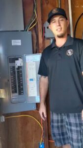 An electrician from Elving Electric standing next to an electrical panel in Marysville, WA