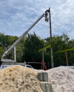 An electrician on a boom lift installing an outdoor pole light at a job site for Joltage LLC in Mobile, AL.