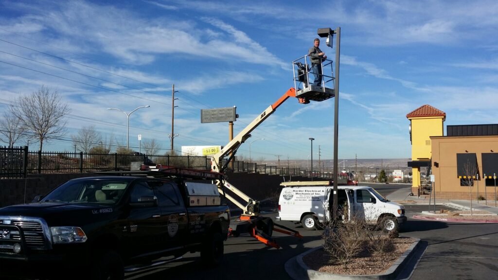 An electrician on a boom lift performing pole light repair for Harder Electrical & Mechanical in Albuquerque, NM.