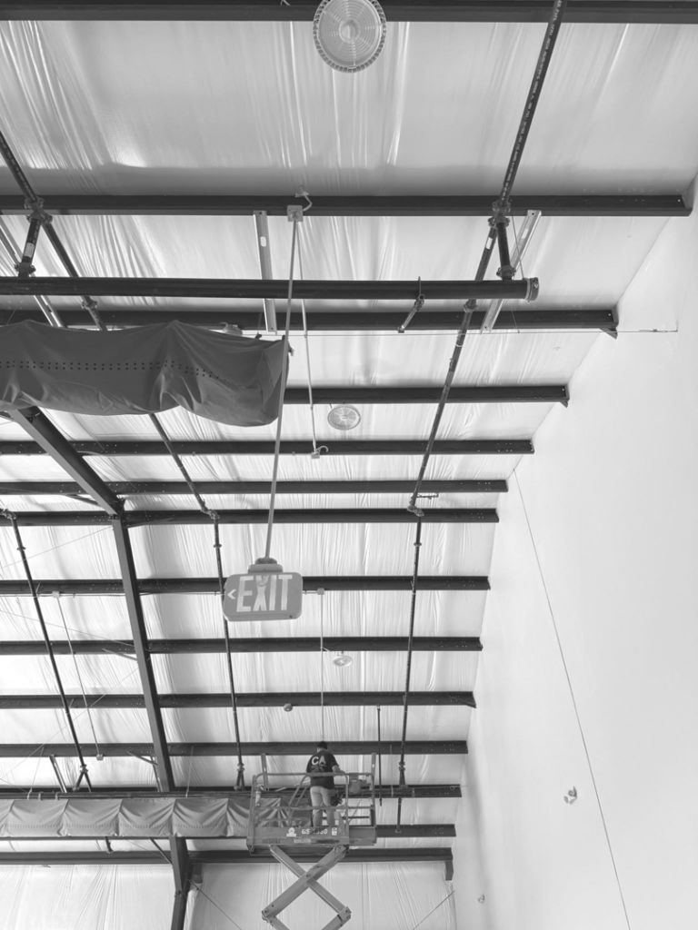 An electrician on a scissor lift installing commercial lighting and wiring in a building for C.A Electrical & More in Greenville, SC.