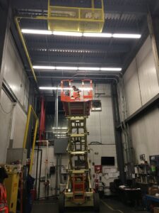 An electrician on a scissor lift installing overhead lighting in a commercial building by RHS Electrical Services in Westerville, OH.