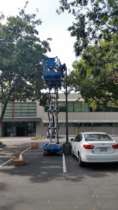 An electrician on a scissor lift working on a tall light pole for Guzman Electric in Sacramento, CA.