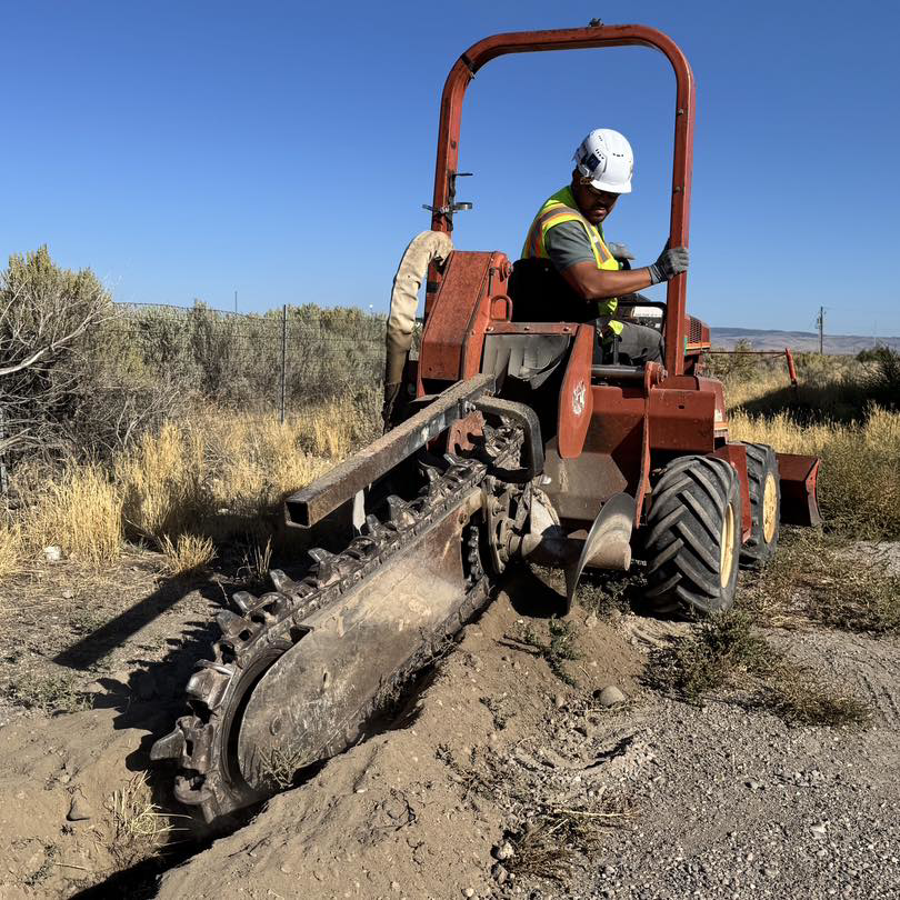An electrician operating a trenching machine for underground electrical wiring installation by Wheeler Electric, Inc. in Idaho Falls, ID.