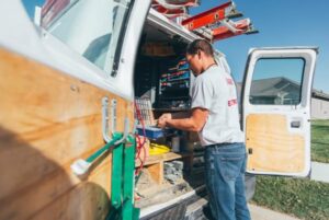 An electrician organizing tools and supplies inside a Brase Electrical Contracting Corp service van in Omaha, NE.