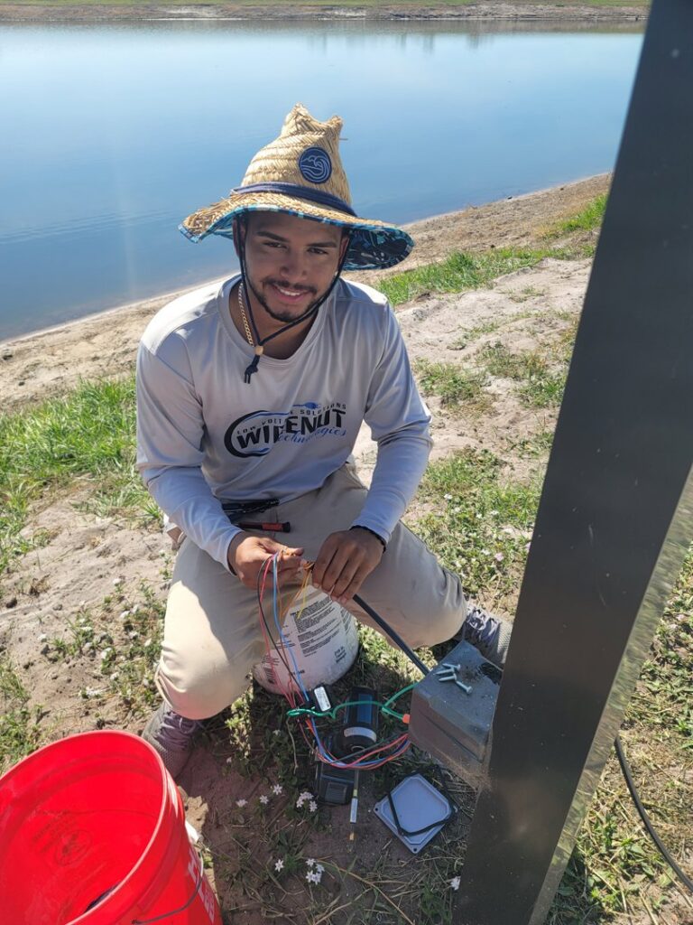 An electrician performing outdoor wiring installation near a body of water for Wirenut Technologies LLC in Brandon, FL.