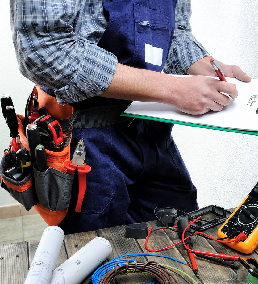 An electrician with a tool belt writing notes, planning a project for Thompson Electric in Elizabethtown, KY.