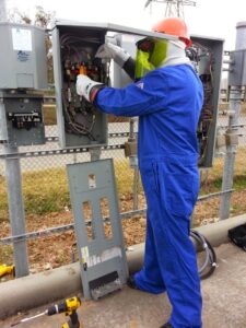 An electrician in full protective gear working on an outdoor electrical panel for Sterling Wiring Solutions in Pearland, TX.
