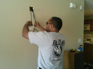 An electrician from BMB ELECTRIC LLC pulling electrical wires from a wall during a job in Columbus, OH.