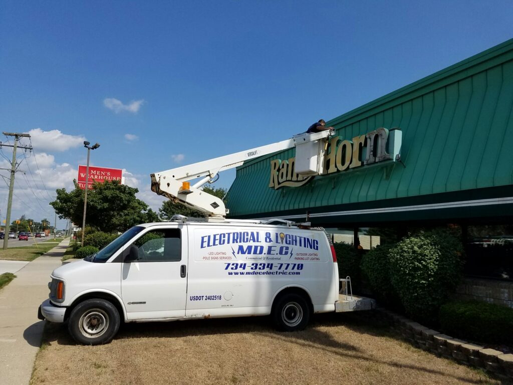 An electrician from MDEC Electrical & Lighting repairing a commercial sign for Ram's Horn restaurant in Livonia, MI.