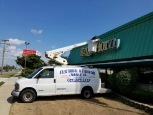 An electrician from MDEC Electrical & Lighting repairing a commercial sign for Ram's Horn restaurant in Livonia, MI.