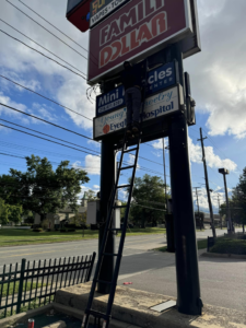 An electrician from Power Electric repairing a commercial sign from a ladder in De Leon springs, FL.