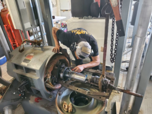 An electrician repairing an industrial electric motor at Caddell Electric Co Inc in Dallas, TX.