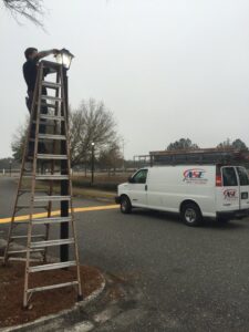 An electrician from All Service Electric repairing an outdoor light fixture in Jacksonville, FL.