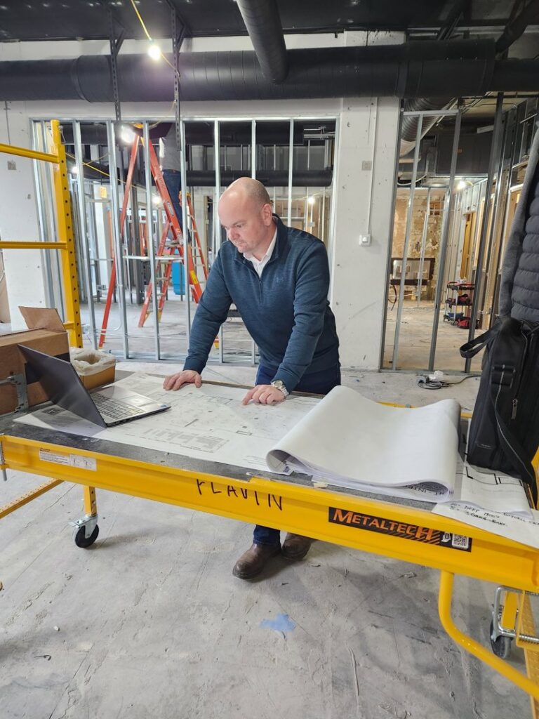 An electrician from Flavin Electric, LLC reviewing blueprints on a construction site in Chicago, IL