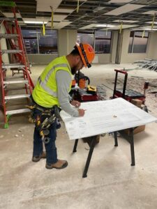 An electrician from Shark Electric reviewing electrical blueprints on a construction site in Houston, TX.