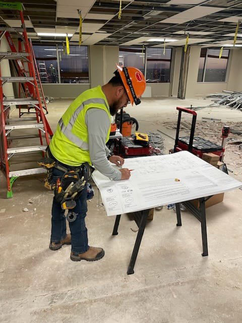 An electrician from Shark Electric reviewing electrical blueprints on a construction site in Houston, TX.