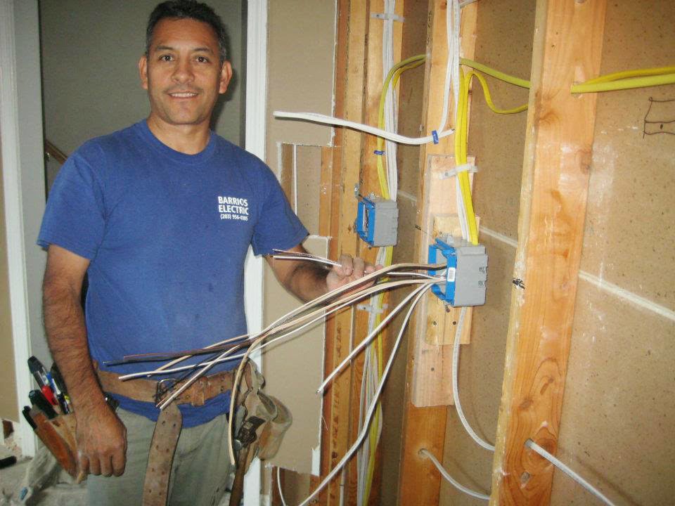 An electrician from Barrios Electric LLC performing rough-in wiring installation in a wall in Norwalk, CT.