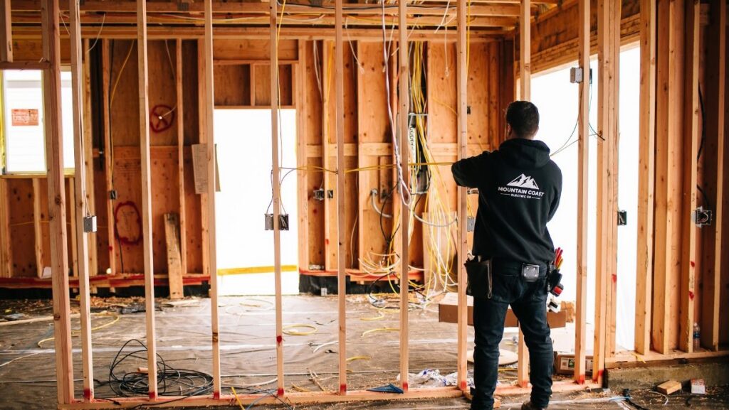 An electrician performing rough-in wiring in a new construction framed wall for Mountain Coast Electric in Salem, OR