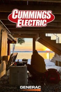 An electrician from Cummings Electric servicing a Generac standby generator outdoors in South Burlington, VT