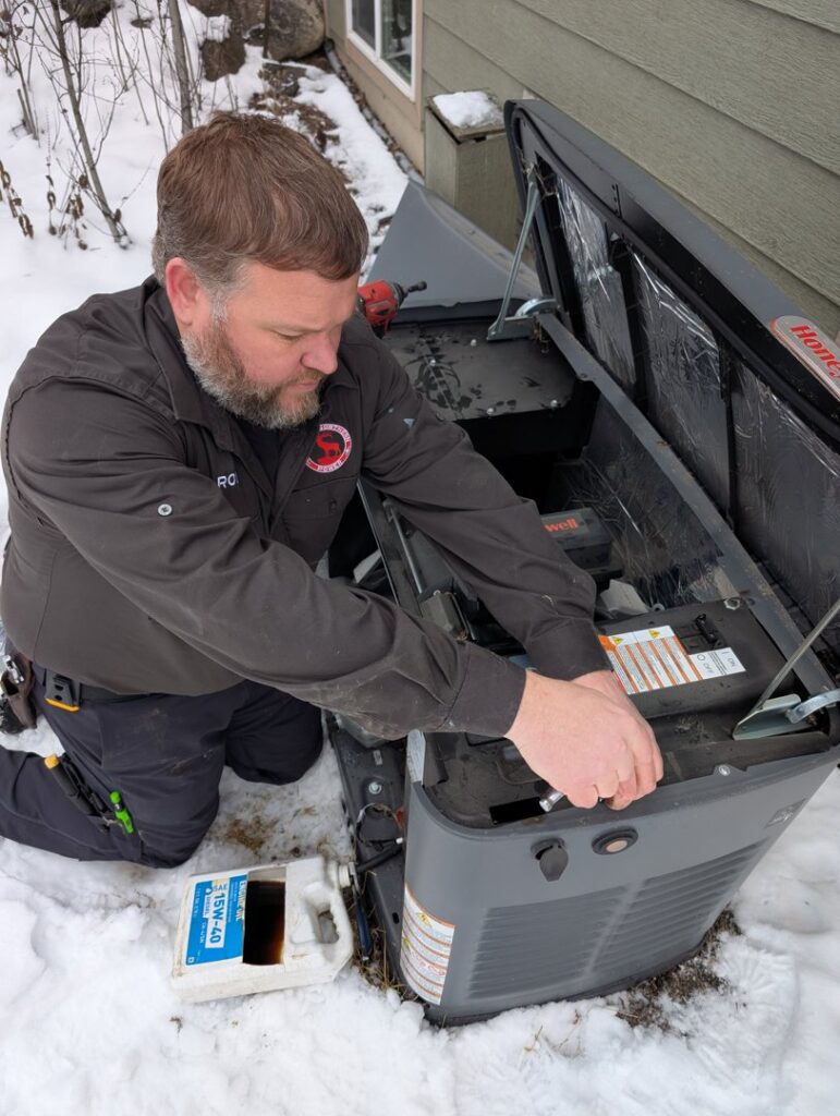 An electrician servicing an open generator in the snow for Great Northern Power in Kalispell, MT.