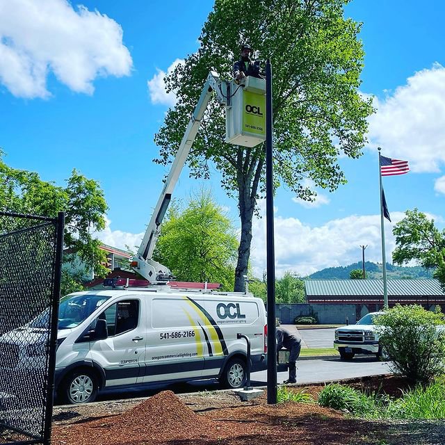 An electrician from Oregon Commercial Lighting servicing a tall light pole from a bucket truck in Eugene, OR.
