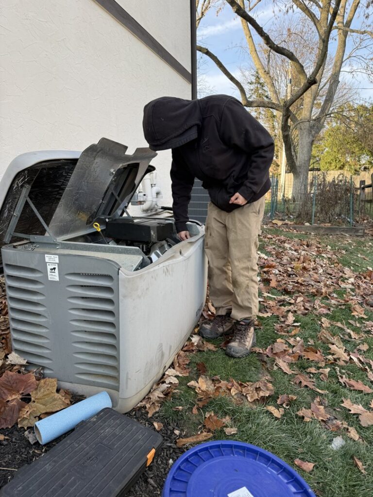 An electrician inspecting and servicing an outdoor standby generator for Buckeye Electric of Upper Arlington, LLC in Columbus, OH.