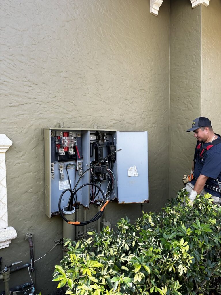An electrician from Bee Electrical Contracting servicing an outdoor electrical panel in Port Saint Lucie, FL.