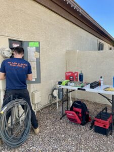 An electrician servicing an outdoor electrical panel with tools laid out on a table by Miller and Sons Electric in North Myrtle Beach, SC.