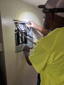 An electrician servicing an electrical panel with wires visible, providing expert service from Carolina Voltage in Charlotte, NC.
