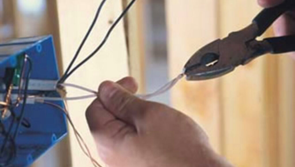 An electrician stripping and connecting wires to an electrical box, performed by Accuracy Electric Incorporation in Lakewood, CO.