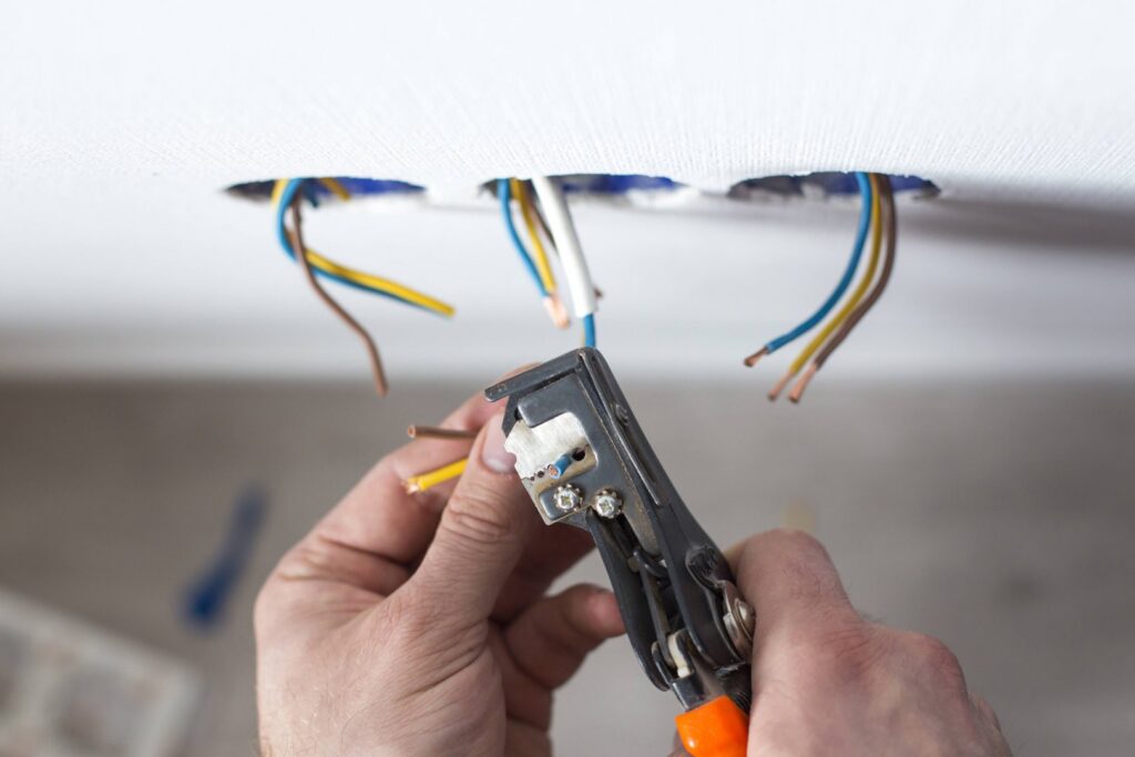 An electrician stripping electrical wires for installation in a wall by Polsley Electric Company in Omaha, NE