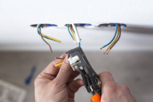 An electrician stripping electrical wires for installation in a wall by Polsley Electric Company in Omaha, NE