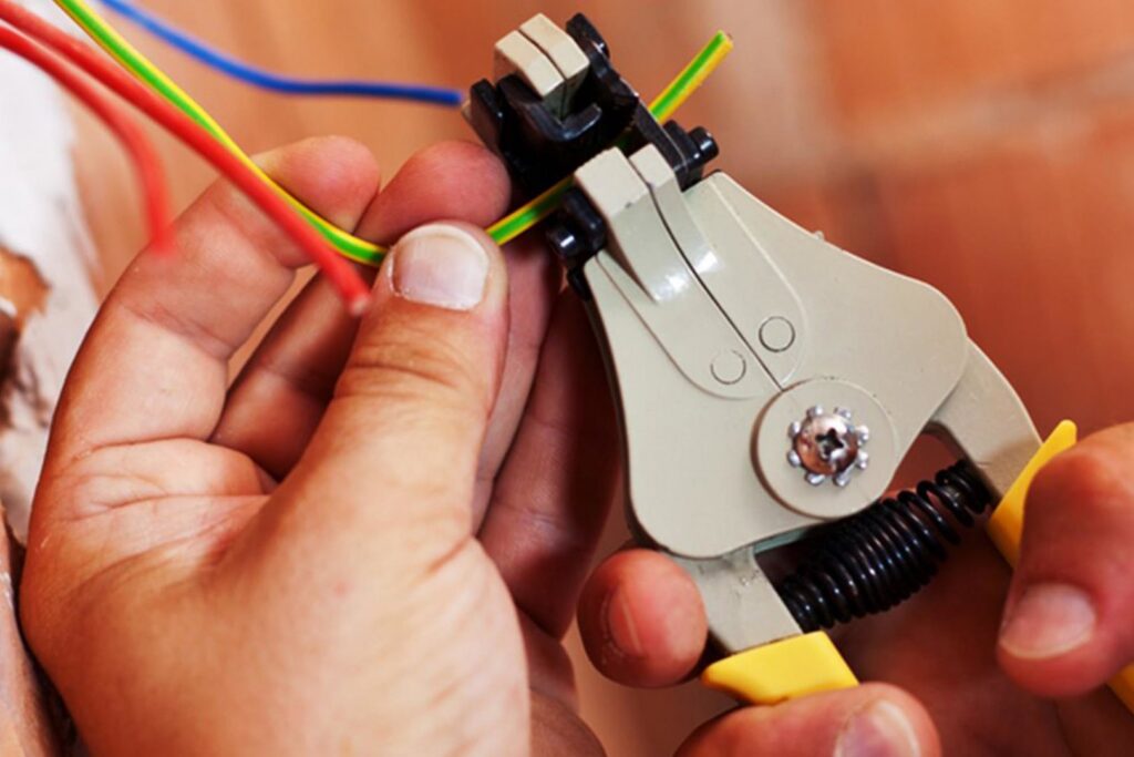 An electrician stripping electrical wires with a tool for New Revelation Technologies LLC in Nampa, ID.
