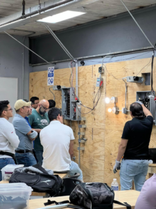 Electrician students training on electrical panels and wiring in a workshop at Escuela Tecnica ABC in North Chicago, IL