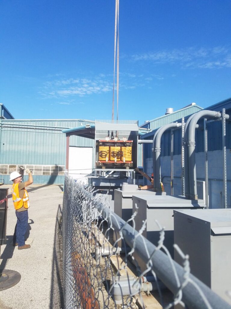 An electrician supervising the lifting and installation of a large electrical transformer for Dobson Electric, Inc. in Jacksonville, FL.