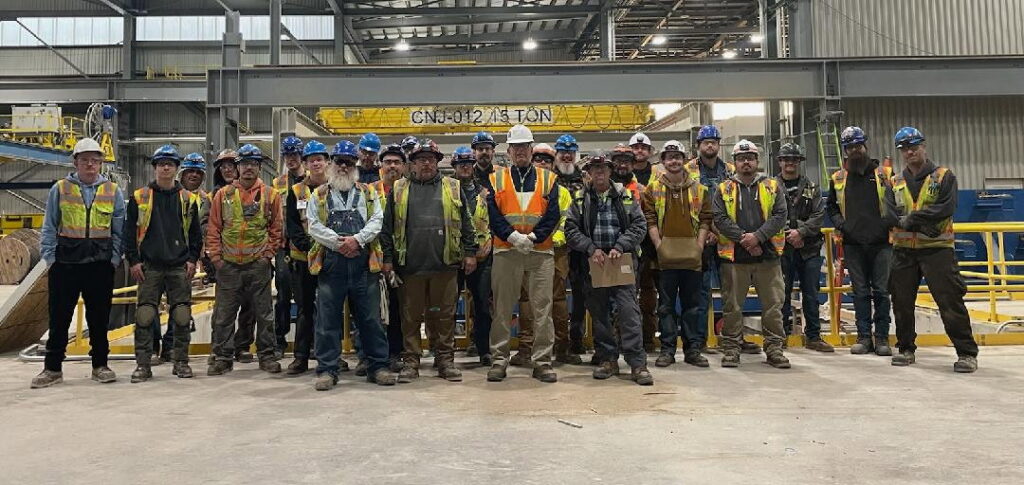 A team of electricians and tradespeople in hard hats and safety vests inside an industrial facility, representing Pueblo Electrics, Inc. in Pueblo, CO.