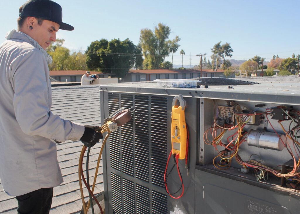 An electrician testing an AC unit's control panel with a multimeter for Cool Aid Air Conditioning in Scottsdale, AZ