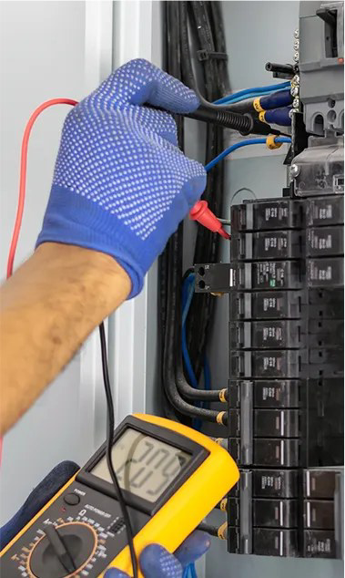 An electrician testing a breaker panel with a multimeter at Hawkins Electric Service, Inc. in Laurel, MD.